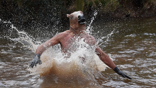 A competitor dressed as a horse jumps into water during the annual Tough Guy Challenge race in Telford, England on Sunday