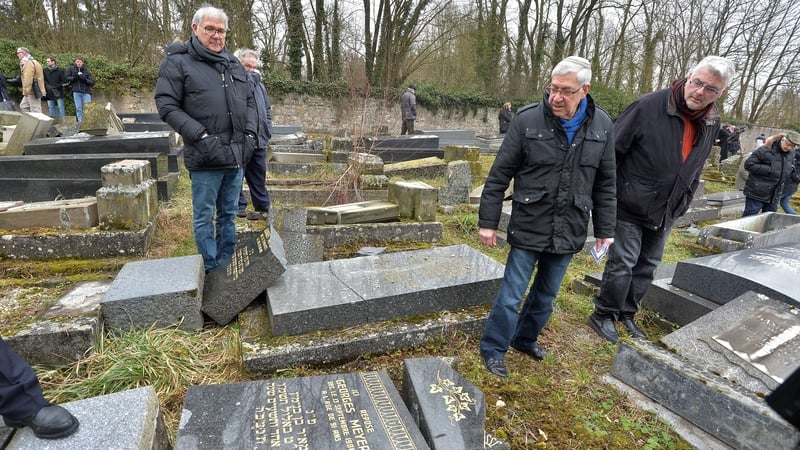 Members of the Jewish community look at the broken tombstones in Sarre-Union