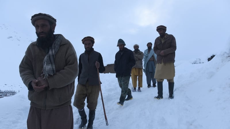 Relatives walk down from the site after searching for the victims of avalanches in the district of Bazarak