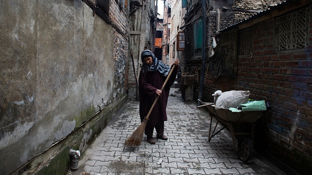 A worker sweeps a road in Kashmir, India