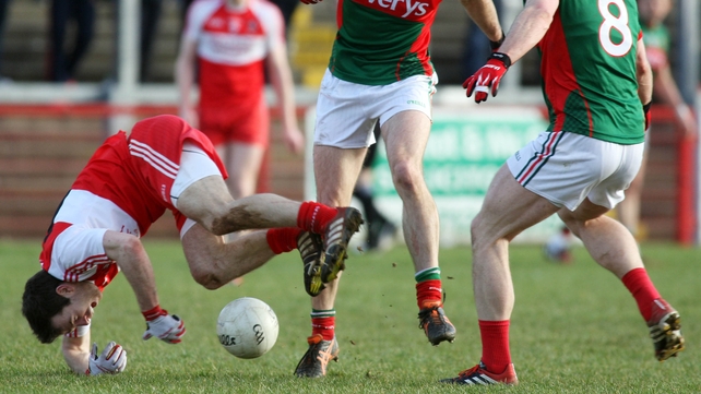 Derry's Daniel McKinless takes a tumble under pressure from Mayo players