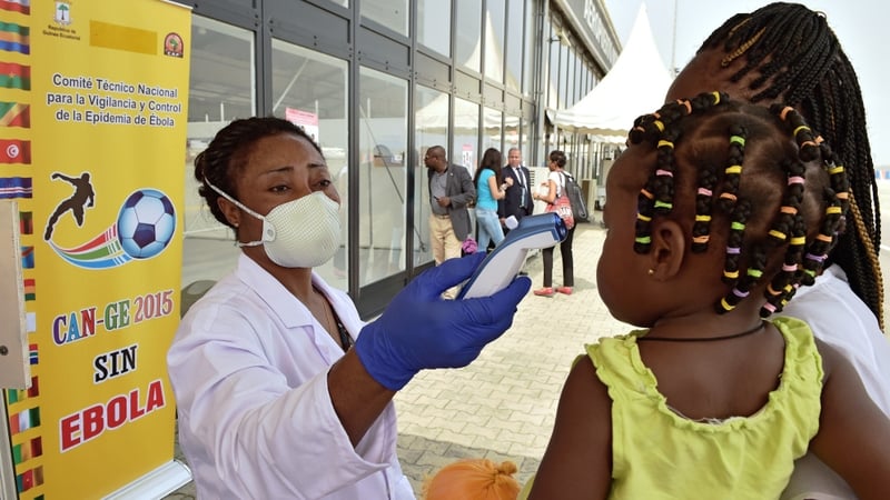 A healthworker takes the temperature of a child and her mother in Sierra Leone