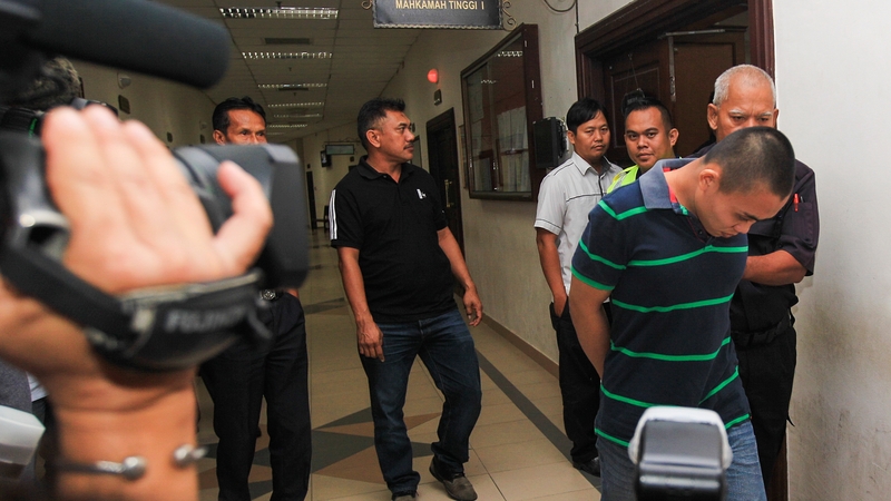 Malaysian police escort Zulkipli Abdullah (R) to the courthouse in Kuching, Sarawak, Malaysia