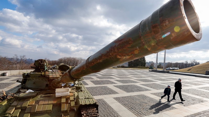 A man and boy pass a tank said to have been seized from separatist rebels in the armed conflict in eastern Ukraine