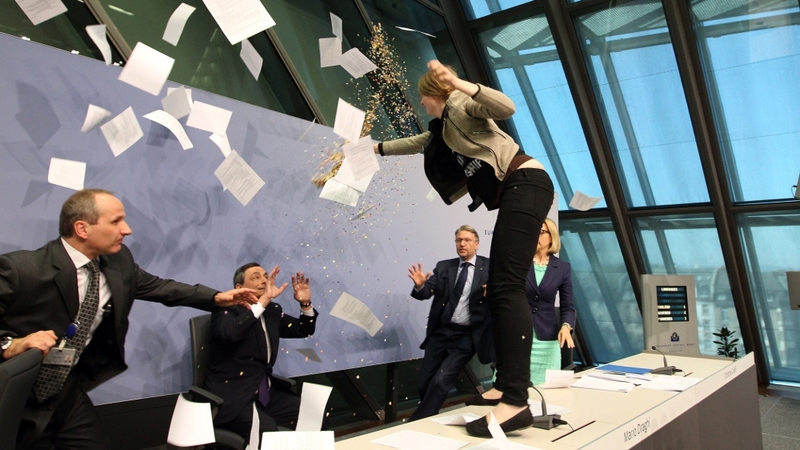 The protester threw paper and glitter at Mario Draghi before being taken away by security