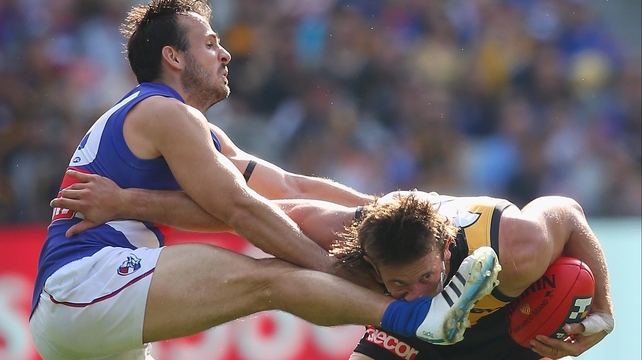 Ivan Maric of the Tigers takes a kick to the nose from Tory Dickson of the Bulldogs during AFL match at Melbourne Cricket Ground