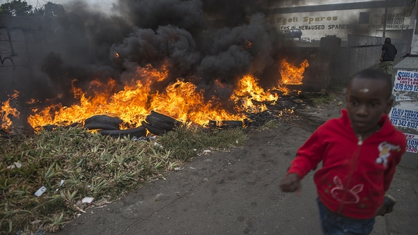 A child runs pass burning tires in the Jeppestown area of central Johannesburg