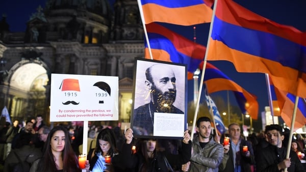People hold a vigil outside a church service commemorating the centenary of the massacre