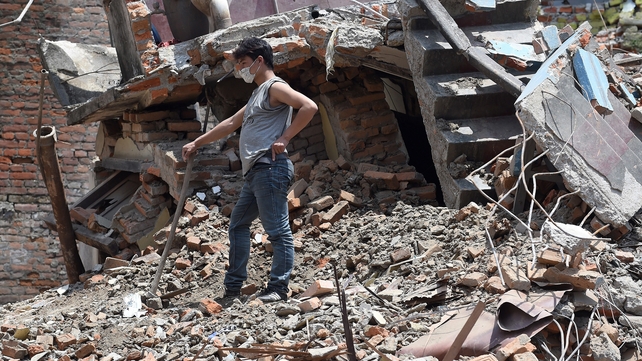 A man clears debris from his damaged house in the capital city, Kathmandu