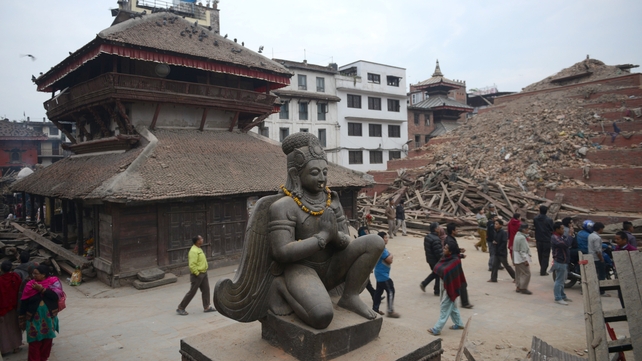 People walk past buildings destroyed by the earthquake