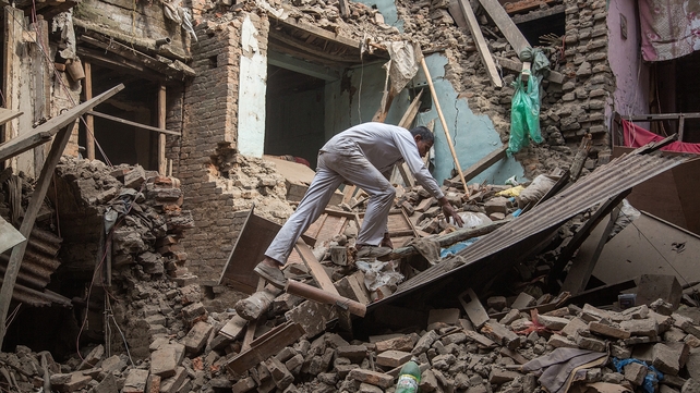 A man climbs on top of debris after buildings collapsed in Bhaktapur