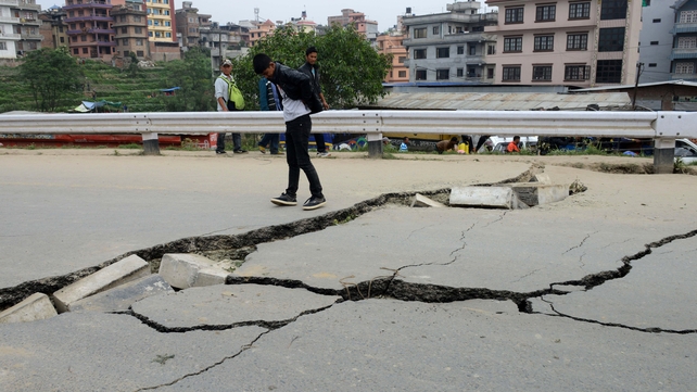Residents inspect damage caused to a road in Kathmandu