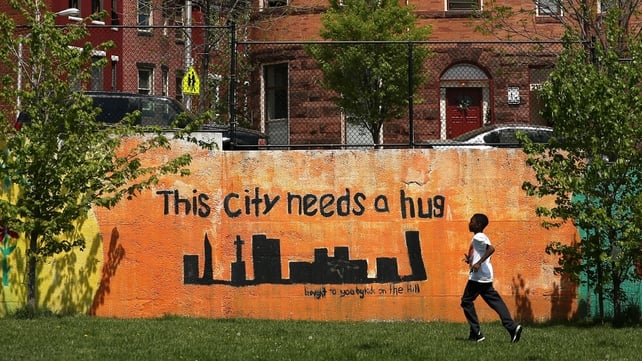 A man runs by a mural in Baltimore following days of unrest over the killing of a black man in police custody