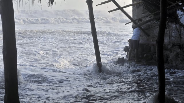 A man tries to protect himself during a strong ocean swell in La Libertad, 34 km south of San Salvador