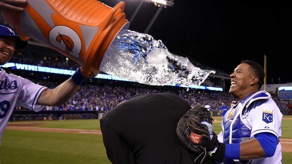 Salvador Perez of the Kansas City Royals uses broadcaster Joel Goldberg as a buffer as team-mate Erik Kratz attempts to douse him with water