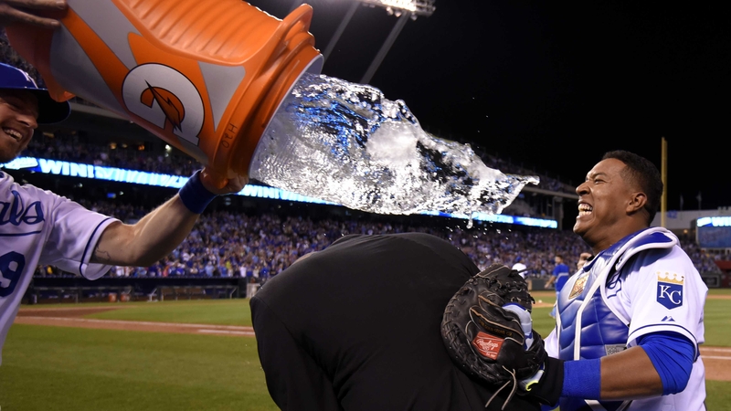 Salvador Perez of the Kansas City Royals uses broadcaster Joel Goldberg as a buffer as team-mate Erik Kratz attempts to douse him with water