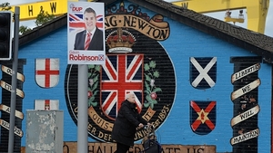 A woman makes her way past election posters for Gavin Robinson of the DUP in Belfast