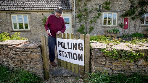 A voter enters a polling station in the Old Post Office in the village of Brokenborough in Wiltshire, England