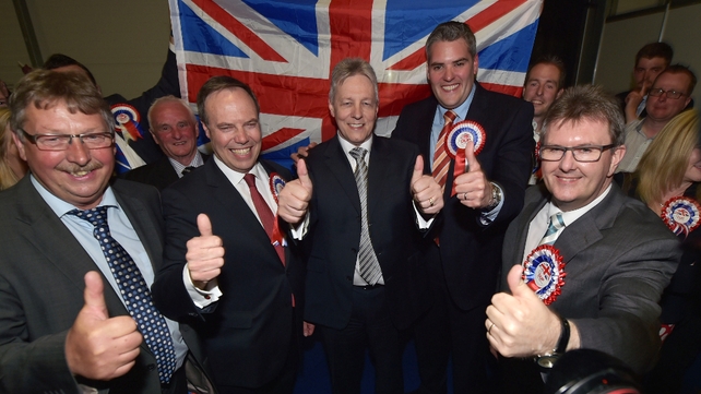Nigel Dodds (2nd L) celebrates with Peter Robinson (C) and Gavin Robinson (2nd R) after his win in Belfast