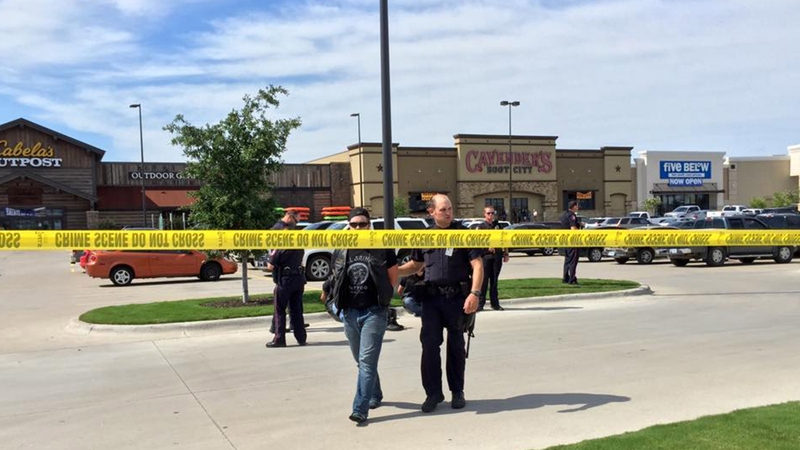 A police officer leads a man away from the scene of the shooting in Waco
