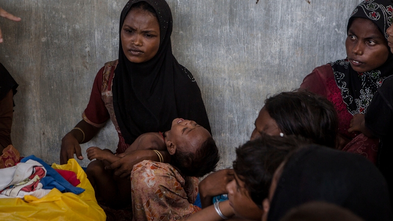 A migrant woman holds her crying child as she rests in Julok village in Kuta Binje, Aceh Province