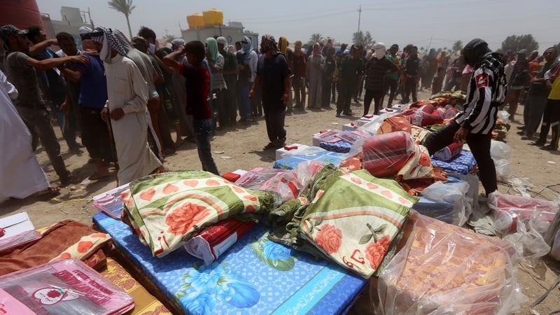 Families who fled the city of Ramadi after it was seized by IS group militants, queue to receive aid at a camp in Amiriyat al-Fallujah