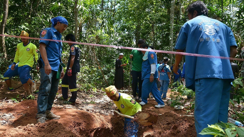 Rescue workers at a site where shallow graves containing 26 bodies were found near Padang Besar in the southern Thai province of Songkhla