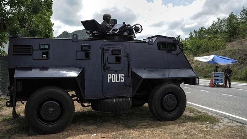 A Malaysian policeman mans an armoured vehicle a day after the government announced the discovery of camps and graves