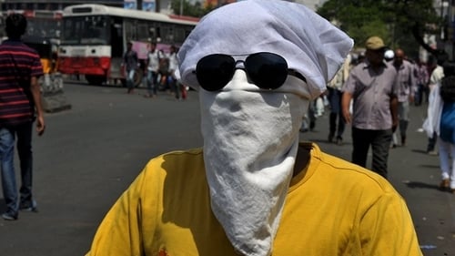 A man covers his face as he drives on a scooter in Hyderabad