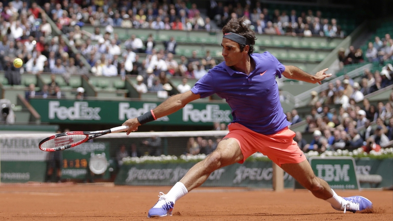 Roger Federer slides for a backhand return at Roland Garros