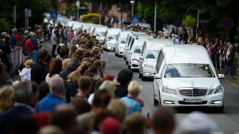 Students from the Joseph-Koenig-Gymnasium high school watch as hearses carrying the remains of 16 of their fellow students and two teachers drive slowly past