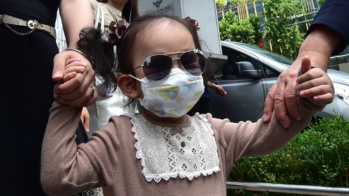 A little girl wears a face mask as the death toll in MERS outbreak continues to rise