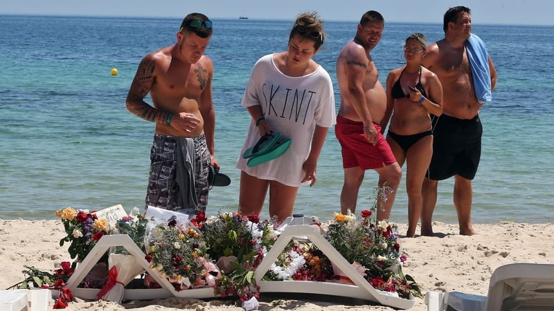 People gather to lay flowers on the beach where 39 people were killed in the terrorist attack