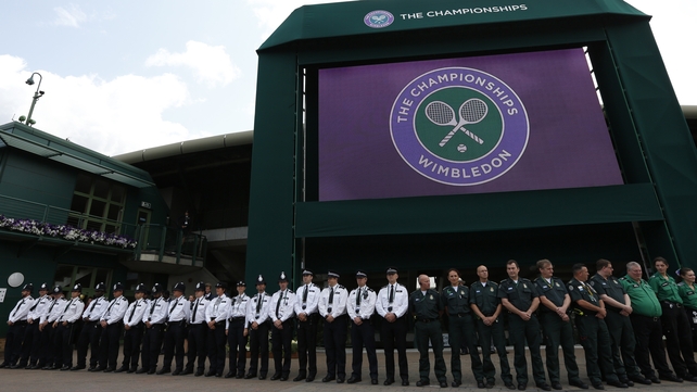 Members of the emergency services stand in a line under the big screen at the back of No 1 Court in Wimbeldon to observe a minute's silence
