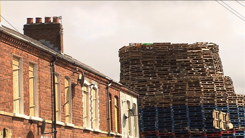 The wood is stacked so high it towers over houses