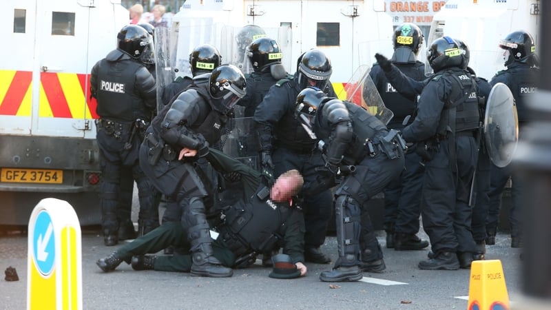 A police officer is dragged away after being struck by an object thrown by loyalist protesters