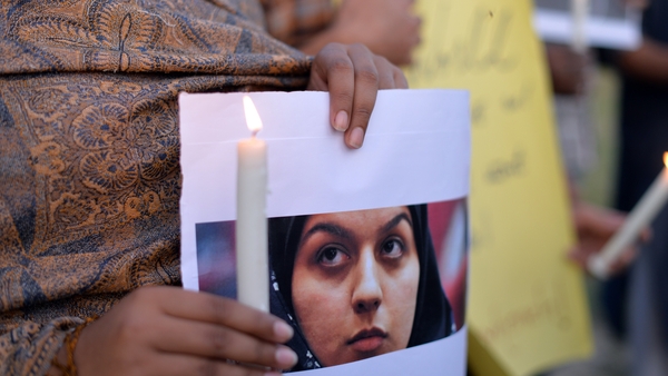 An activist holds a photograph of a woman who was hanged in Iran