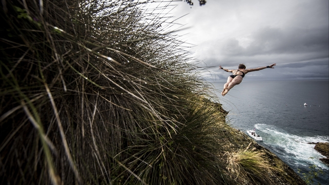 Ginger Huber dives from a 20 metre cliff at the Red Bull Cliff Diving World Series at Islet Franca do Campo, Portugal