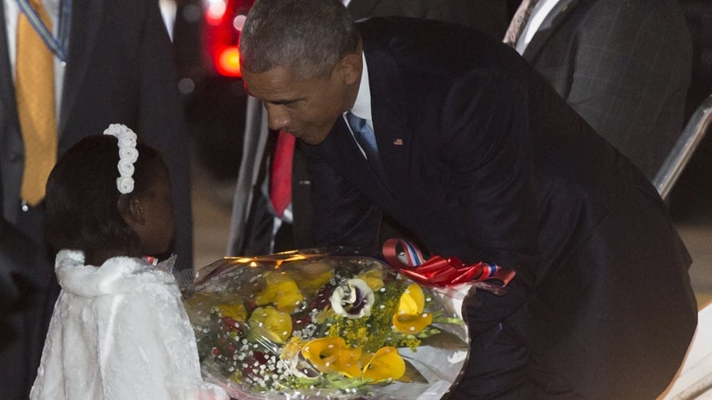 Barack Obama receives flowers from Joan Wamaitha, 8, upon his arrival at Kenyatta International Airport