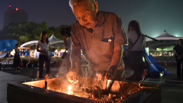 A man lights a fire in the incense to pray for the victims of the 1945 atomic bombing