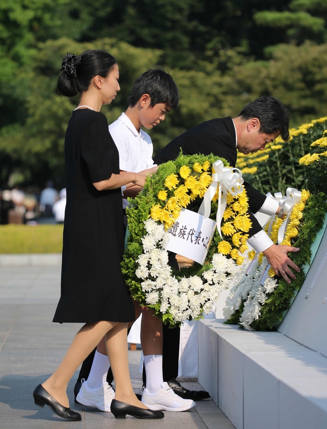 Relatives of A-bomb victims offer flower wreaths on an altar