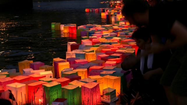 People float peace messages written on paper lanterns along the river during the 70th anniversary activities