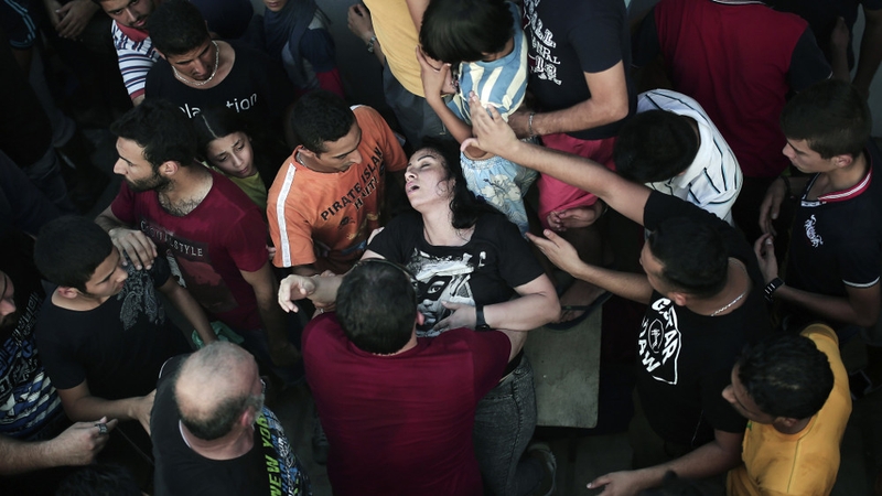 A woman faints as hundreds wait for immigration papers in Kos