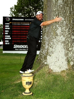 Shane Lowry hugs a tree near the 18th green with the Gary Player Cup after winning the Bridgestone Invitational at Firestone