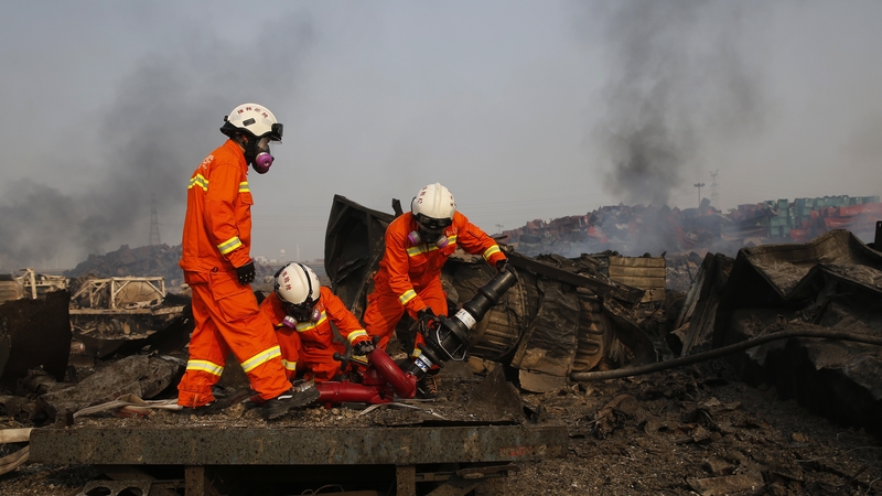 Firemen wearing gas masks prepare to combat fresh fires in the area of a huge explosion that rocked the port city of Tianjin