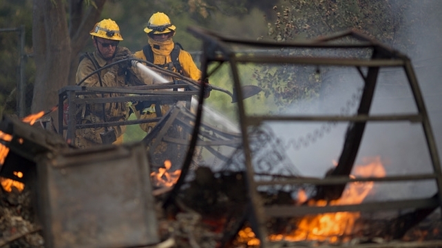 Firefighters hose down the smoldering ruins of a building at the Warm Springs Rehabilitation Center, California