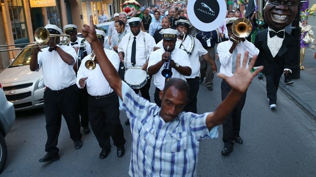 A marching band winds through the streets of the French quarter as festivities continue into the evening