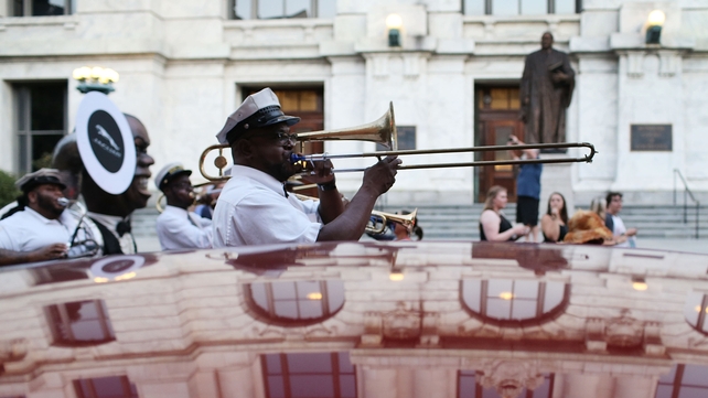 A marching band winds through the streets of the French Quarter during anniversary commemorations