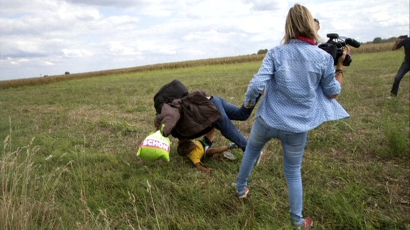 The woman can be seen tripping a man who was running with a child in his arms
