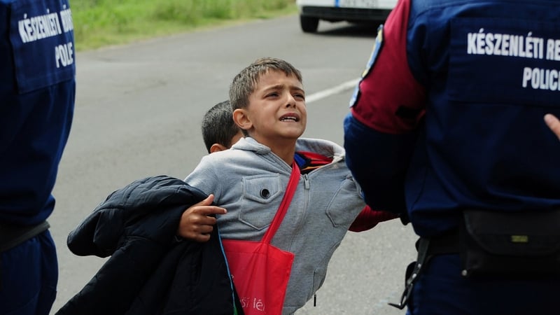Police officers hold a child after a crowd broke out of at a refugee collection point near Roszke at the Hungarian-Serbian border